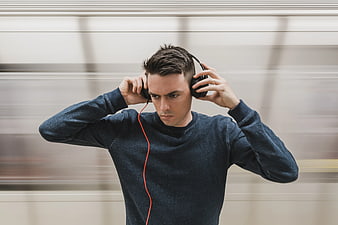 Young man listening to music with headphones against motion blur