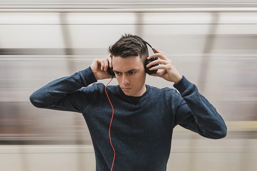 Young man listening to music with headphones against motion blur