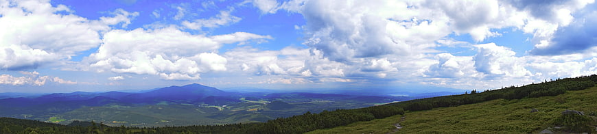 Panoramic mountain landscape with green hills and blue sky