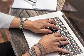 Woman Typing on Laptop at Outdoor Wooden Table