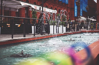 Urban fountain with water jets and blurred colorful foreground