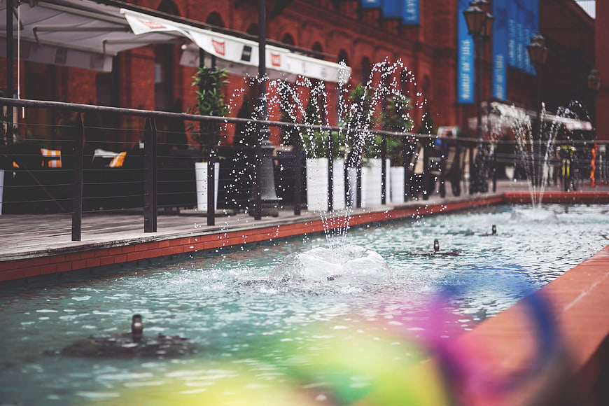 Urban fountain with water jets and blurred colorful foreground
