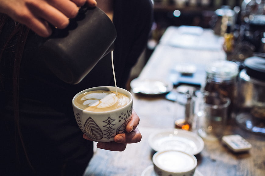 Barista Pouring Latte Art into Patterned Coffee Cup
