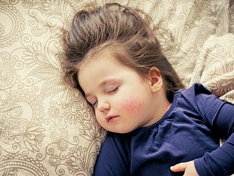 Sleeping Toddler Girl With Messy Hair On Patterned Bedding