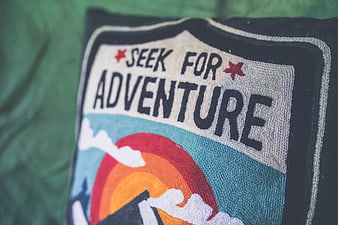 Close-up of embroidered 'Seek for Adventure' patch on dark fabric