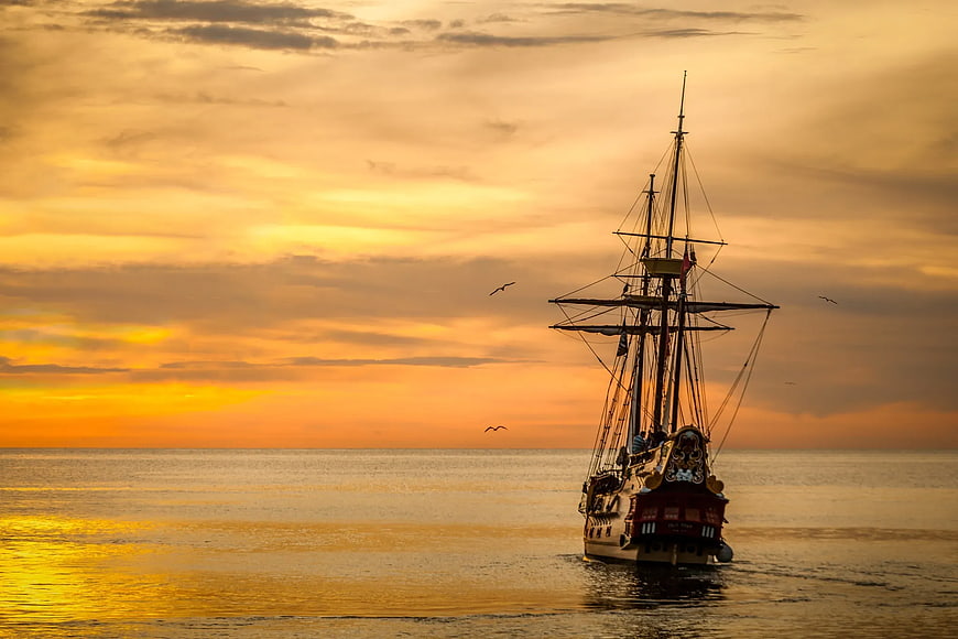 Silhouette of Tall Ship Sailing at Golden Sunset
