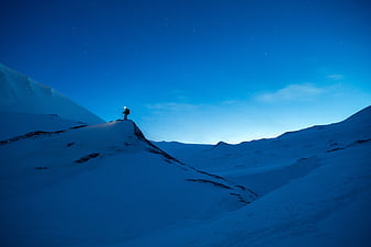 Lone Hiker Silhouette on Snowy Mountain Ridge Under Starry Night Sky