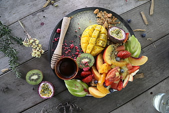Overhead View of Colorful Fruit Bowl with Honey and Granola on Rustic Wood