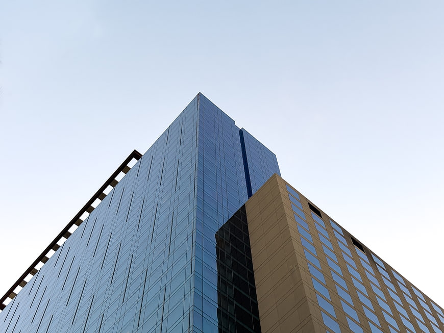 Low angle view of modern glass skyscraper against blue sky