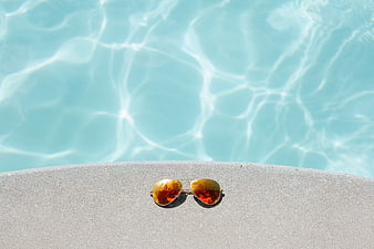 Aviator Sunglasses on Poolside Edge with Blue Water