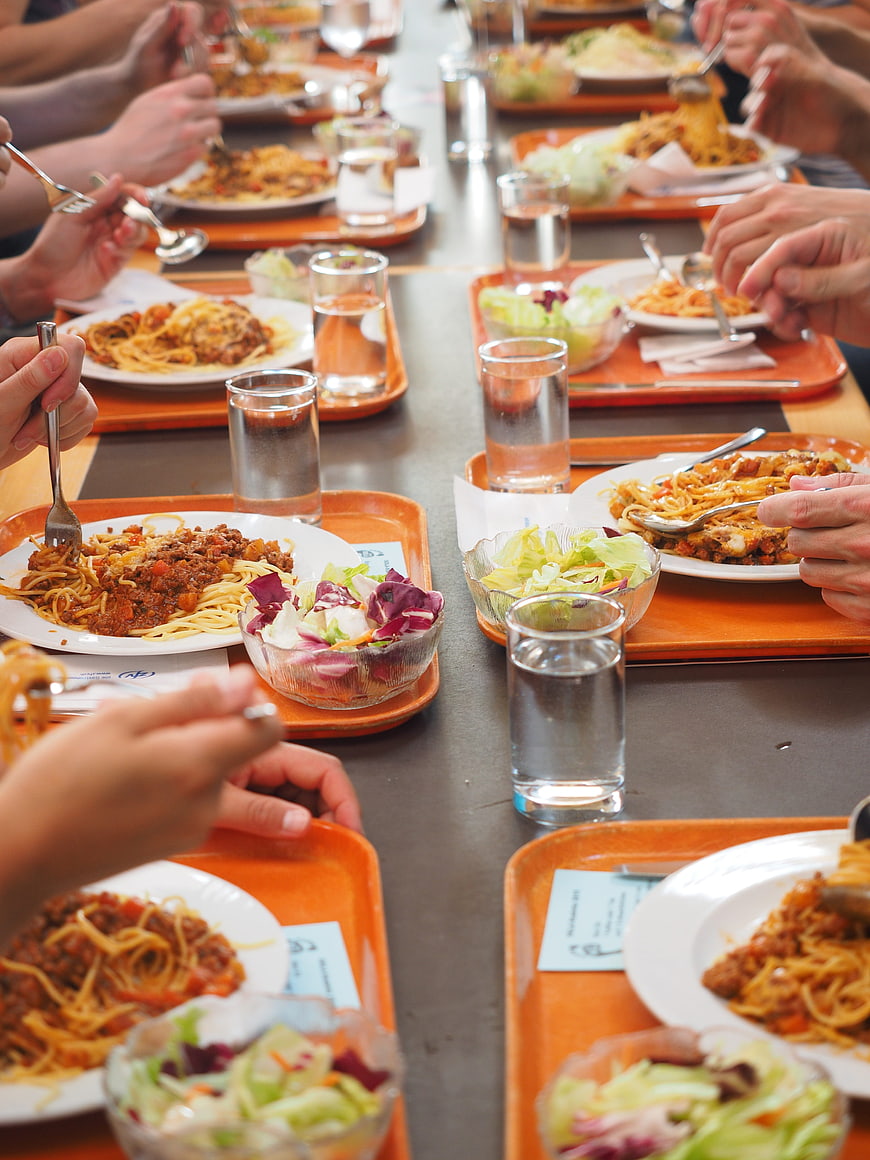 Group eating spaghetti lunch in cafeteria