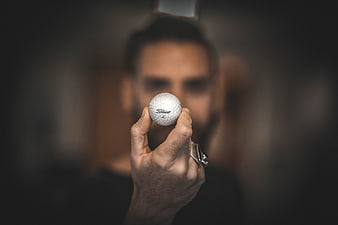 Man holding golf ball close up with blurred background
