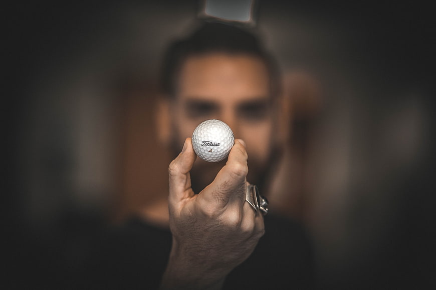 Man holding golf ball close up with blurred background