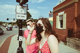 Couple wearing face masks and sunglasses on city street