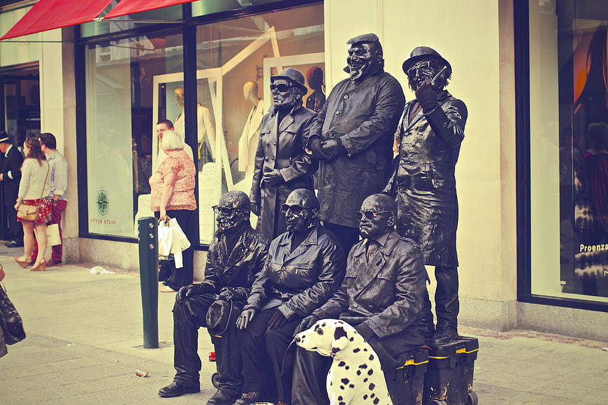 Street Performers Painted Black as Living Statues on Sidewalk