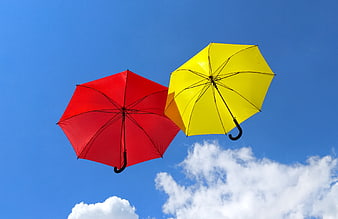 Red and yellow umbrellas floating against blue sky