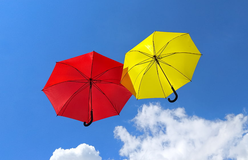 Red and yellow umbrellas floating against blue sky