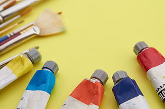 Colorful paint tubes and brushes on yellow background