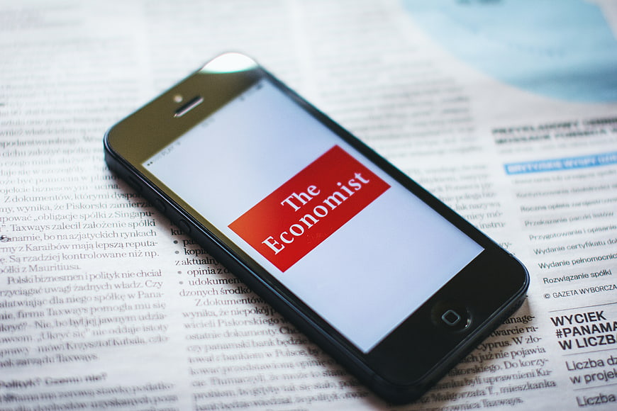 Smartphone displaying The Economist app on newspaper