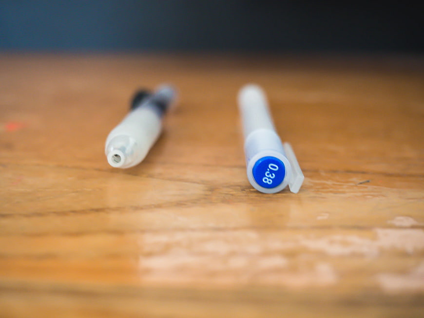 Close-up of two pens on a wooden desk surface