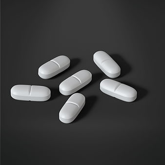 White oval pills scattered on dark gray background