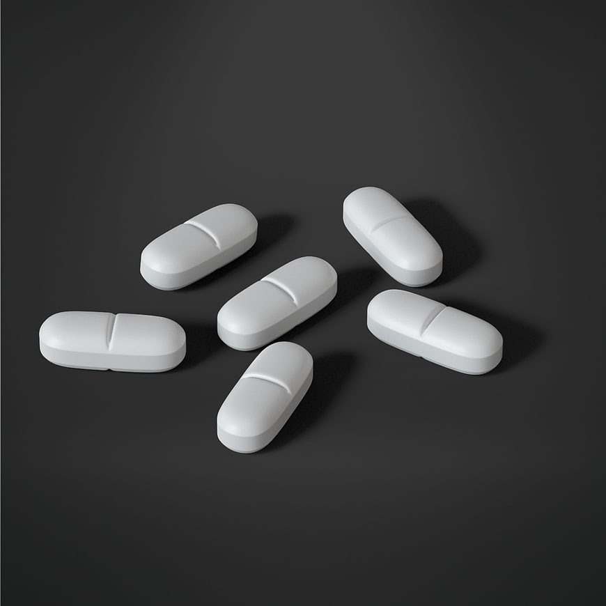 White oval pills scattered on dark gray background