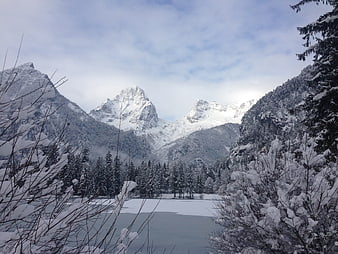 Snowy mountain landscape with frozen lake and pine trees