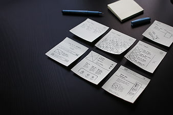 UX wireframes and sticky notes on dark desk