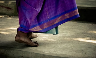 Bare feet walking in purple saree on concrete