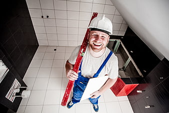 Happy construction worker holding spirit level in bathroom