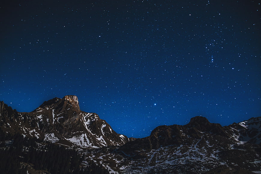 Starry Night Sky Over Snowy Mountain Peaks