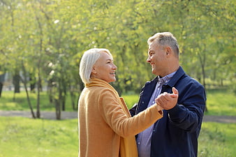 Happy senior couple dancing in a sunny park