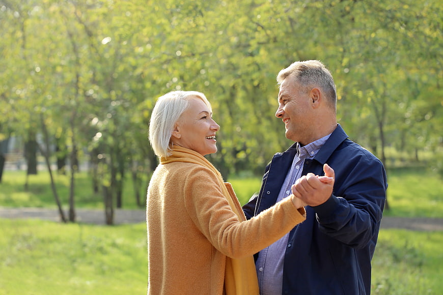 Happy senior couple dancing in a sunny park