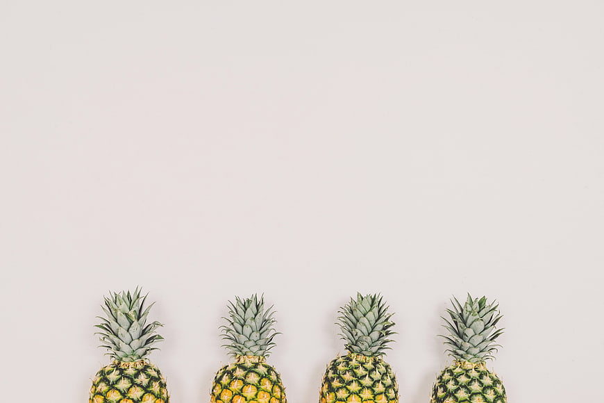 Row of pineapples on white background with copyspace