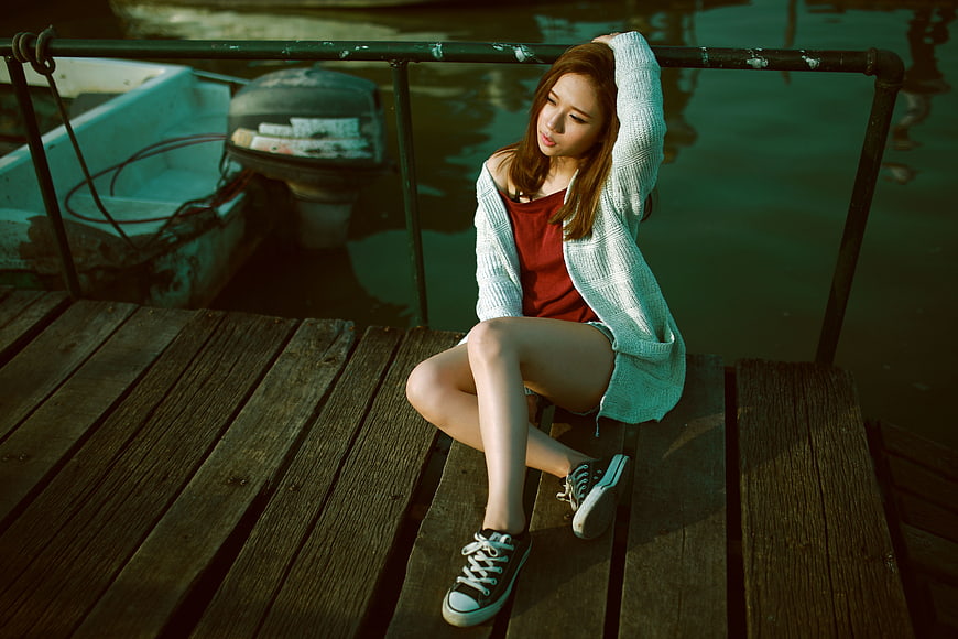 Young woman sitting on wooden dock by boat