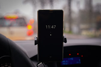 Smartphone in car mount displaying time on dashboard