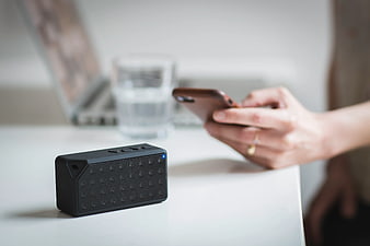 Black Portable Bluetooth Speaker on White Desk with Smartphone