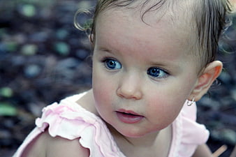 Close-up portrait of a baby girl with blue eyes and pink dress