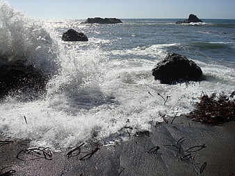 Ocean waves crashing against rocks on a sandy beach