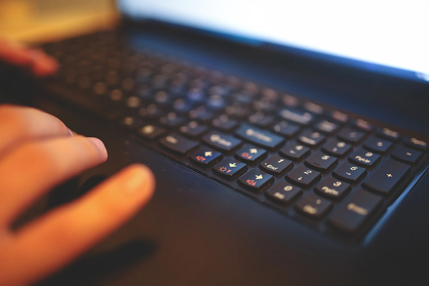 Close-up of hands typing on a laptop keyboard