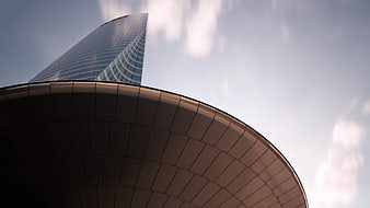 Modern Skyscraper and Curved Architecture Against Blue Sky