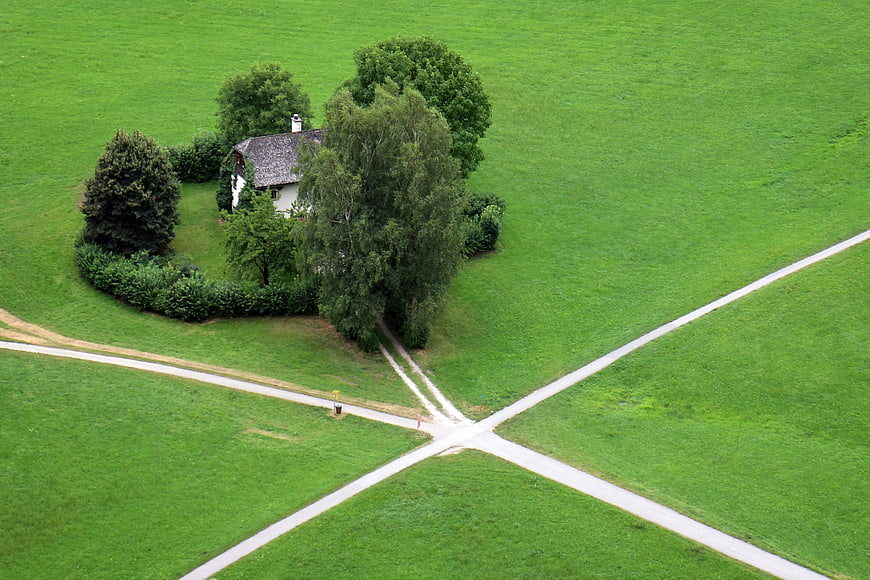 Aerial view of rural house at crossroads in green field