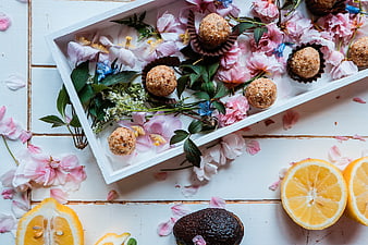 Healthy energy balls with flowers and citrus on white wood