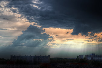 Dramatic storm clouds with sun rays over city skyline