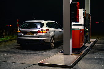 Silver car refueling at gas station at night