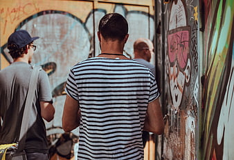 Men Walking Past Graffiti Wall in Urban Street
