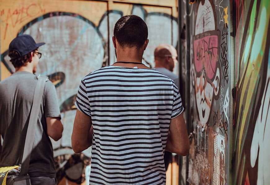 Men Walking Past Graffiti Wall in Urban Street