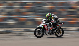 Motorcycle racer leaning into a turn on a race track
