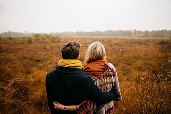 Couple from behind in autumn field with scarves