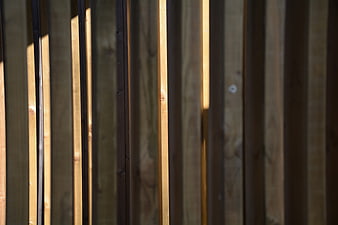 Vertical wooden fence planks with sunlight and shadows